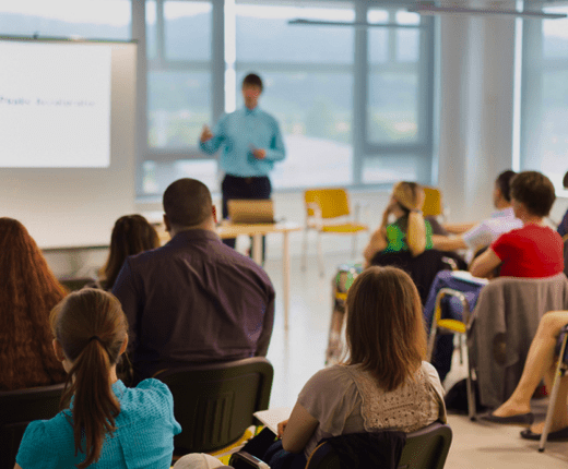 A group of professionals watching a presentation in a modern office setting.