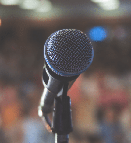Focus on a microphone is a blurred background of an audience.