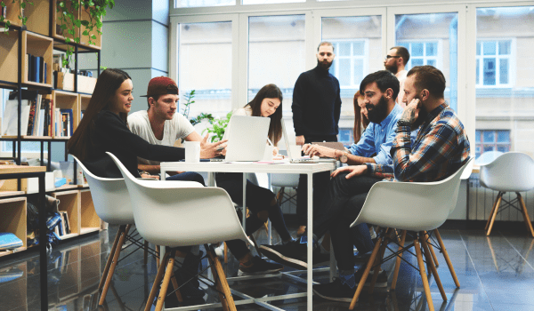 Office scene with people collaborating over a laptop on a desk.